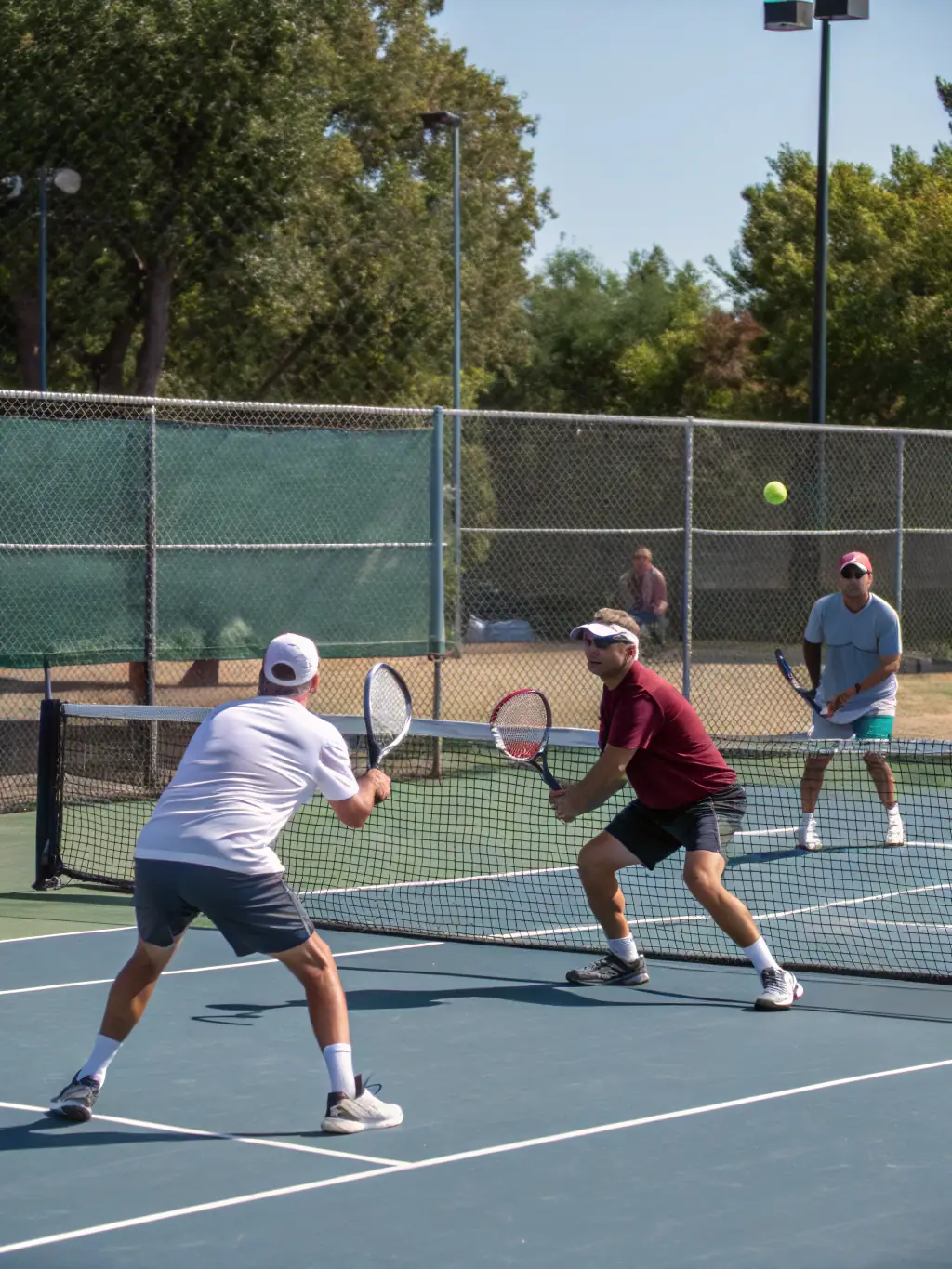 A dynamic shot of adult players engaged in a competitive doubles match on a clay court at CREULLOIS TENNIS CLUB, demonstrating skill and teamwork.